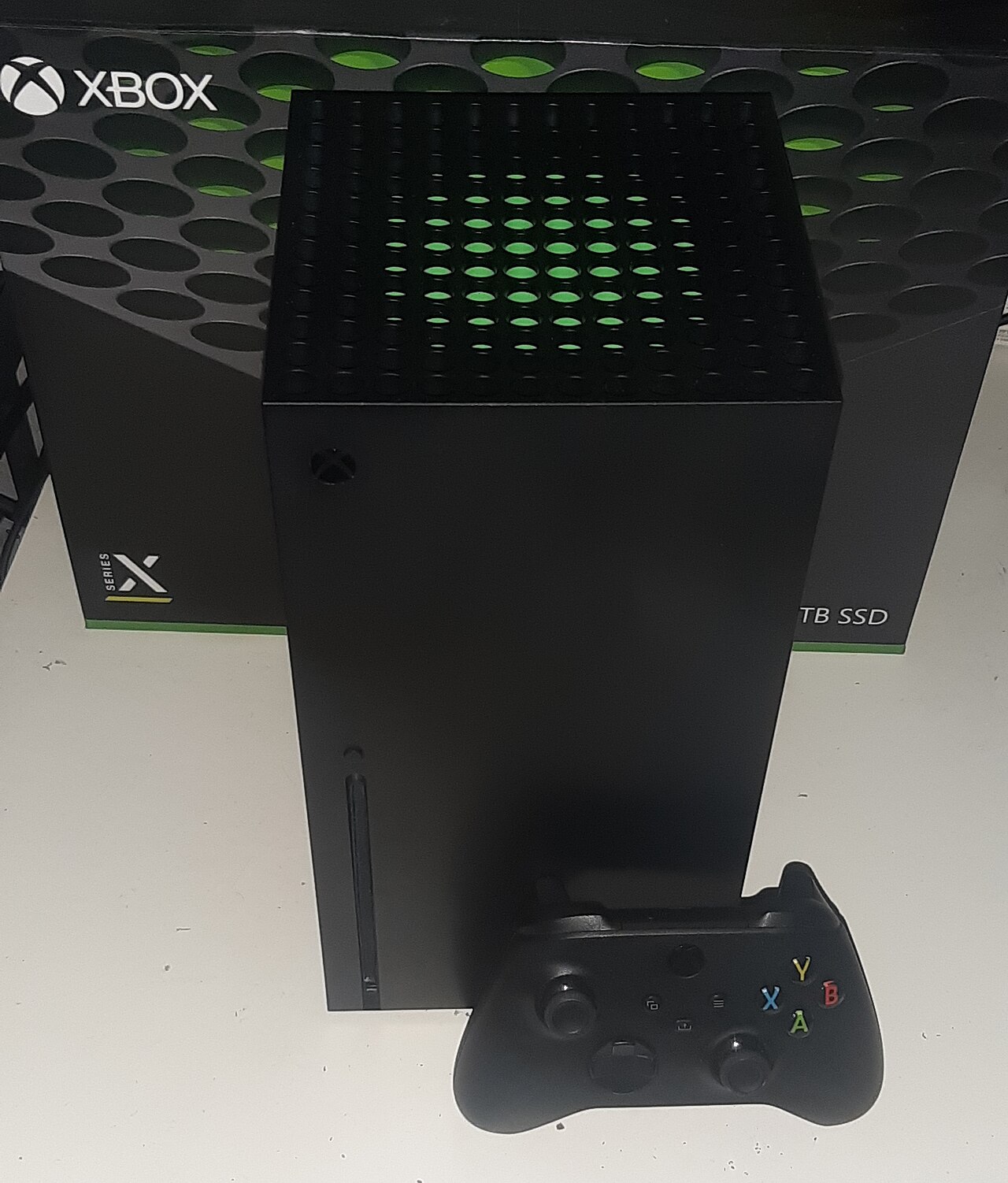 Máy Xbox Series X đặt cạnh hộp và tay cầm