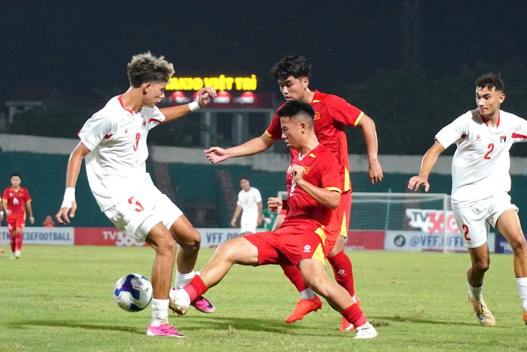 Cầu thủ U20 Việt Nam áo đỏ tranh chấp với hậu vệ U20 Palestine trên sân Việt Trì