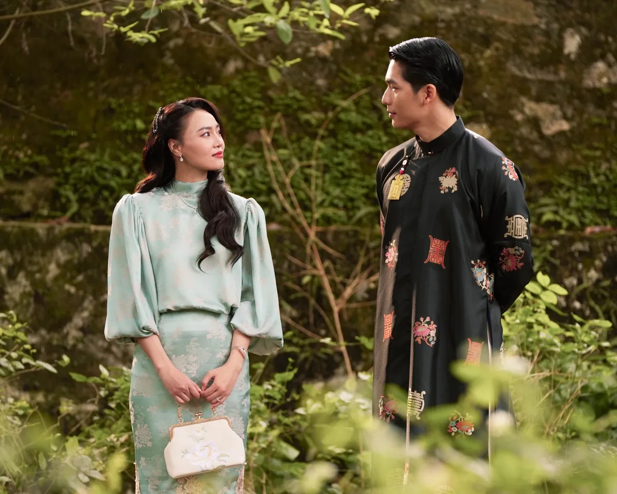 Thị Liễu mặc áo lụa xanh ngọc đứng đối diện Văn Tài mặc áo dài gấm đen giữa vườn cây