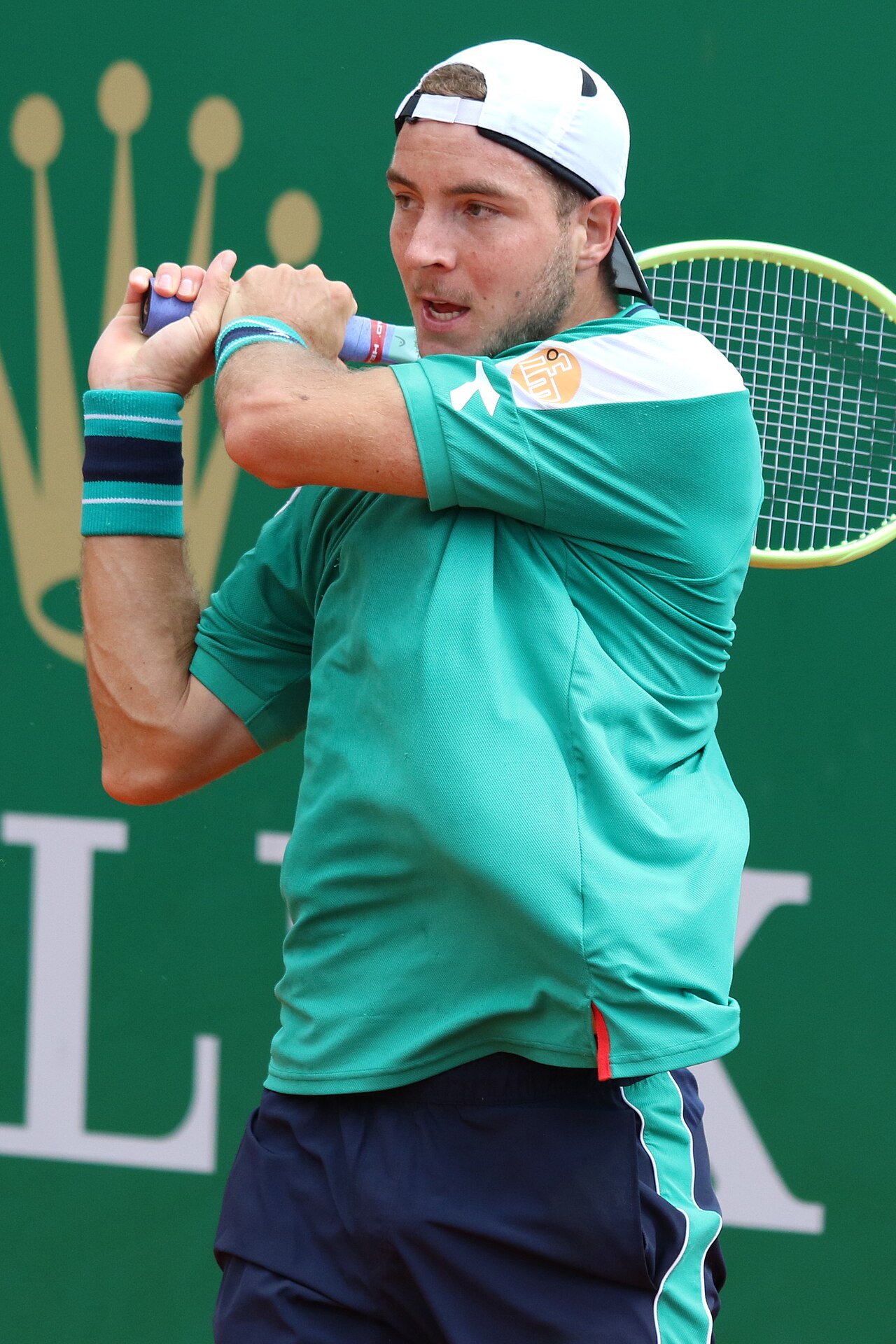 Jan-Lennard Struff đội mũ ngược, mặc áo xanh lá, vung vợt trái tay