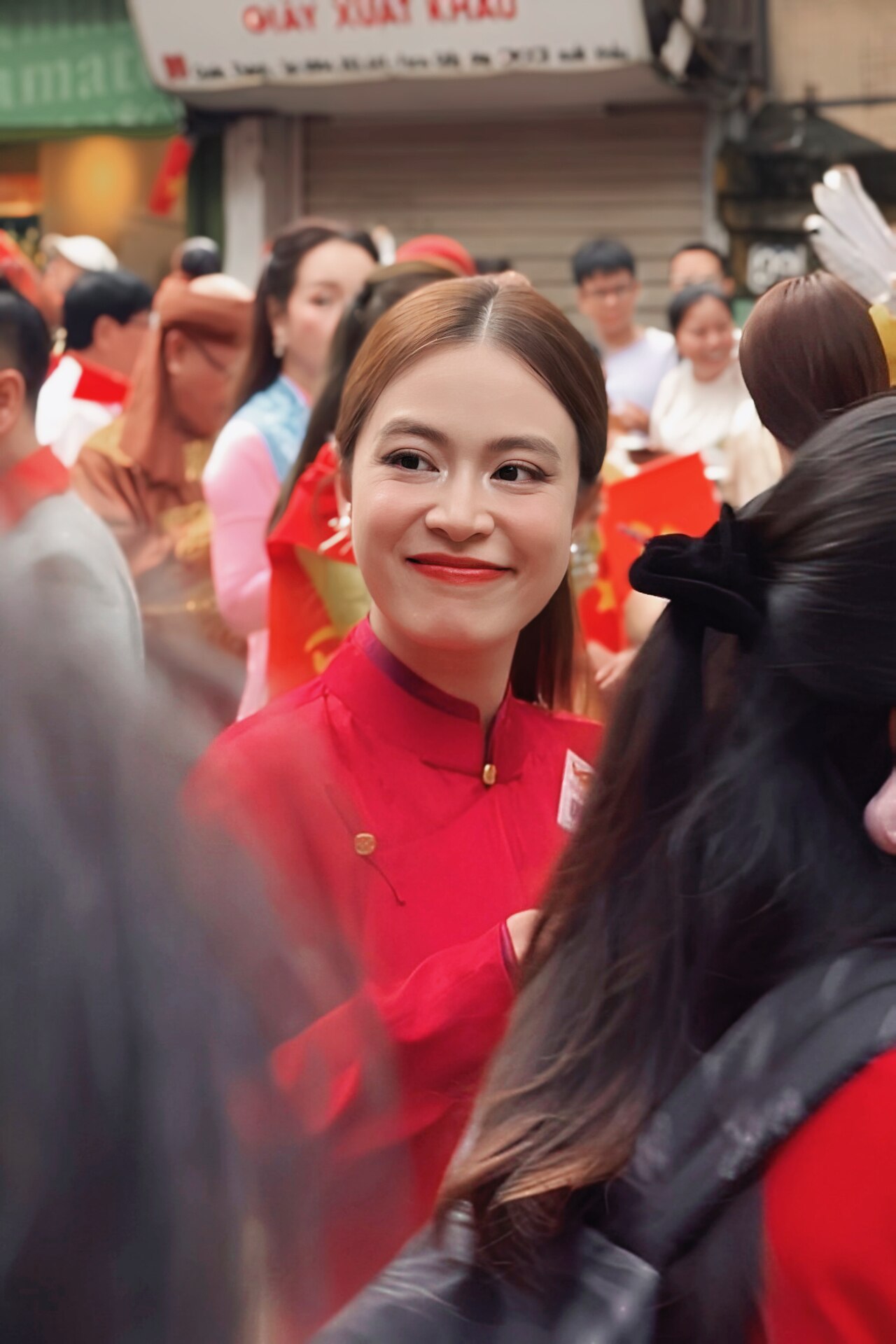 Hoàng Thùy Linh mặc áo dài đỏ, cười, giữa đám đông ở phố cổ Hà Nội dịp lễ diễu hành A80 tháng 9/2025